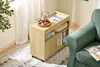 A wooden rolling cabinet with books and tea set next to a green sofa. Podgląd zdjęcia produktu