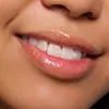 Close-up of a person's lips with glossy pink lip gloss and white teeth. Náhled obrázku produktu