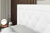 A close-up view of a white tufted headboard of a bed, with a bedside table and lamp visible in the background. Produktbild-Vorschau