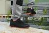 A person wearing work pants and black safety shoes with orange soles is walking up metal stairs outdoors. Produktbild-Vorschau