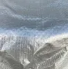 A close-up of a silver, textured cover, likely a table cover, showing its woven pattern and reflective surface. Produktbild-Vorschau