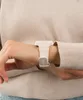 A close-up shot of a person's wrist wearing a white digital watch. Produktbild-Vorschau