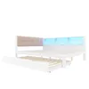 A white wooden bed frame with a beige upholstered headboard and built-in shelves with blue LED lighting. A pull-out trundle bed is visible underneath. Produktbild-Vorschau