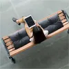 A woman sits on a wooden bench with cushions, using a tablet. Podgląd zdjęcia produktu