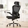 A black ergonomic office chair is shown in a well-lit room with a desk and shelves in the background. Náhled obrázku produktu
