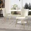 Two beige upholstered dining chairs with gold legs are placed in a dining room setting with a white oval table and a large window overlooking a garden. Anteprima dell’immagine prodotto