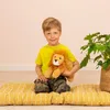 A young boy is sitting on a yellow mat, holding a stuffed lion. Voir les images du produit