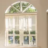 A view through a window with sheer curtains, showing trees and a street outside. Produktbild-Vorschau