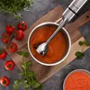 A hand blender is being used to puree tomatoes and lentils in a bowl, surrounded by fresh ingredients. Produktbild-Vorschau
