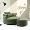 A modern green circular sofa with a matching ottoman in a well-lit room with a shadow of a plant on the wall.