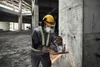 A construction worker is using an angle grinder to cut rebar in a building under construction. Náhľad obrázku produktu