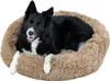 A black and white dog lying in a round, fluffy, light brown dog bed. Produktbild-Vorschau