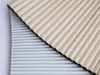 A close-up view of two folded pleated blinds, one in sand color and the other in gray. Anteprima dell’immagine prodotto