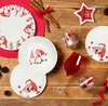 A festive Christmas-themed table setting with plates, glasses, cinnamon sticks, and pinecones. Anteprima dell’immagine prodotto