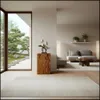 A modern living room with a view of a Japanese garden, featuring a wooden pedestal with a sculpture. Voir les images du produit