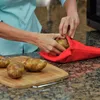A person is placing a potato into a red potato baking bag. Produktbild-Vorschau