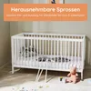 A white baby crib with bedding and toys on the floor in a room. Produktbild-Vorschau