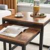 A close-up view of two nesting coffee tables with a rustic wood finish and black metal frames, set in a living room environment. Podgląd zdjęcia produktu