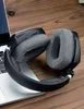 A pair of black and gray headphones rests on a laptop on a wooden surface. Produktbild-Vorschau