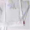 A close-up view of a sheer curtain with a floral print. Produktbild-Vorschau