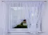 A white lace curtain is shown hanging in a window. Náhled obrázku produktu