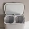 A close-up view of the top of a light gray laundry basket with its lid open, revealing two compartments inside. Produktbild-Vorschau