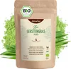 A bag of organic barley grass powder with loose powder and grass blades around it. Produktbild-Vorschau