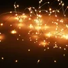 A string of small, warm white LED lights on a thin silver wire, draped and tangled against a dark, gradient background. Produktbild-Vorschau