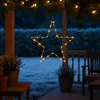A star-shaped LED light decoration hangs from a porch ceiling at night, with a blurred background of a yard and furniture. Voir les images du produit