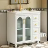 A white bathroom vanity with a ceramic sink and gold fixtures, set against a tiled wall. Produktbild-Vorschau