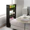 A black four-tier rolling cart filled with various boxes of food items is placed next to a light gray sofa. A round side table with books and a teacup sits on the sofa. Podgląd zdjęcia produktu