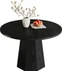 A black round dining table with a vase of flowers and a bowl of apples on it. Produktbild-Vorschau