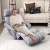 A woman is reading a book while sitting on a gray recliner chair in a living room. Produktbild-Vorschau