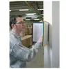 A man in a warehouse is looking at a wall-mounted display system with documents. Anteprima dell’immagine prodotto