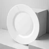 A white plate is placed on a white surface, leaning against a white cube. Anteprima dell’immagine prodotto