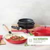 A collection of cookware, including frying pans and a pot, arranged on a surface with some food items and a cutting board. Voir les images du produit