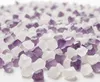 A close-up, shallow depth of field shot of many small, irregularly shaped crystals, some purple and some white, scattered across a white surface. Anteprima dell’immagine prodotto