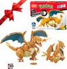 A product collage featuring Mega Construx Pokemon Charizard building sets, a red ribbon bow, and a Pokeball accessory. Voir les images du produit