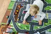 A young child is playing with toy cars on a play mat depicting a town and roads. Produktbild-Vorschau