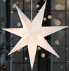 A white paper star lantern hangs in front of a window with blurred bokeh lights. Náhled obrázku produktu