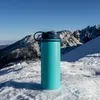 A turquoise water bottle sits on a snowy mountain slope with mountains in the background. Podgląd zdjęcia produktu