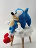 A plush toy of Sonic the Hedgehog sitting on a small, fluffy white stool. Produktbild-Vorschau