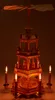 A wooden Christmas pyramid with candles lit around it. Produktbild-Vorschau