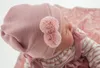 Close-up of a reborn doll wearing a pink knitted hat with pom-poms. Anteprima dell’immagine prodotto