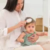 A mother is brushing her baby's hair. Produktbild-Vorschau