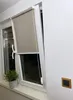 A roller blind is installed on an open window, with a small potted plant on the windowsill. Anteprima dell’immagine prodotto