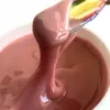 A close-up of a pink gel product being scooped out of a container with a tool that has an iridescent finish. Produktbild-Vorschau