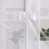 A close-up view of a white fabric curtain with text printed on it and a succulent plant in the background. Produktbild-Vorschau