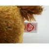 A close-up of a plush toy with a tag attached. Produktbild-Vorschau