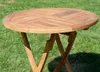 A round wooden garden table with a folding base, set on a grassy lawn. Produktbild-Vorschau